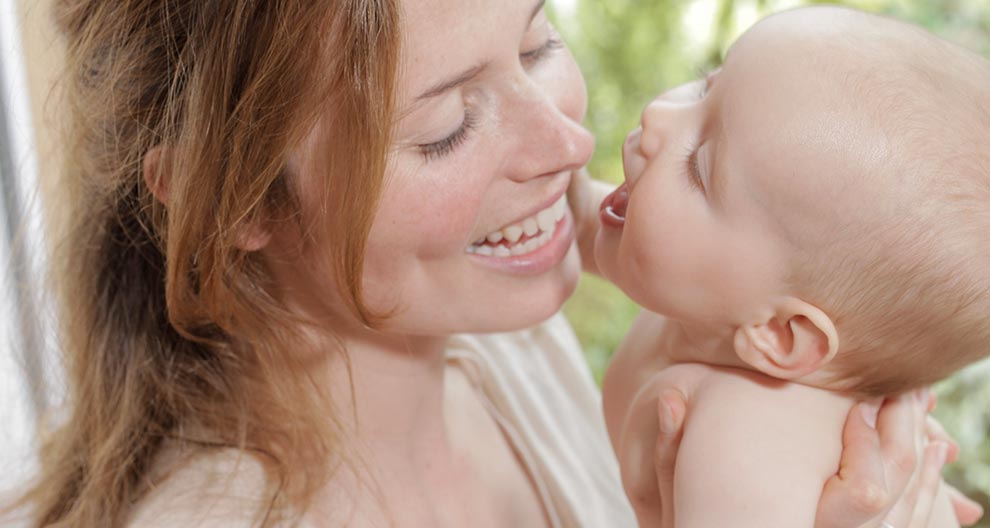 A woman and a baby are in close proximity, with the woman holding the baby close to her face.