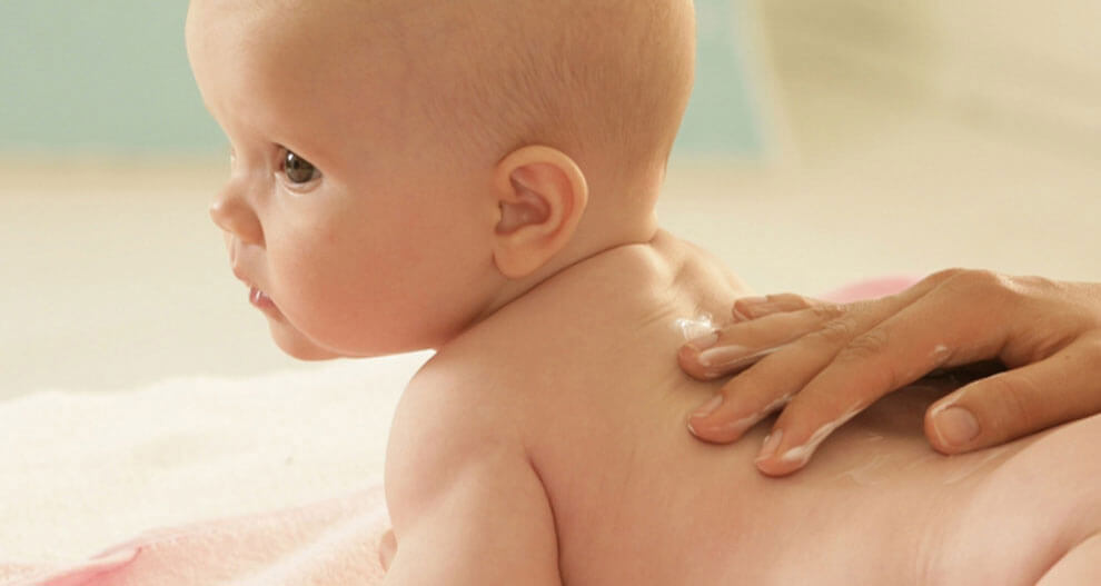 A baby is being massaged with lotion.