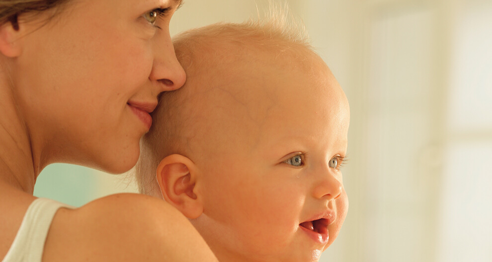 A woman is holding a baby close to her face.