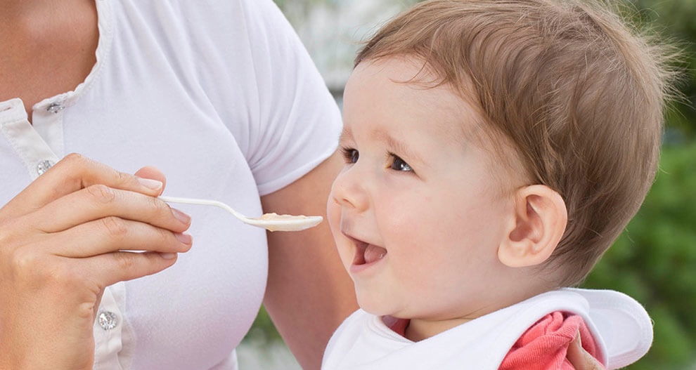 A person is feeding a baby with a spoon.