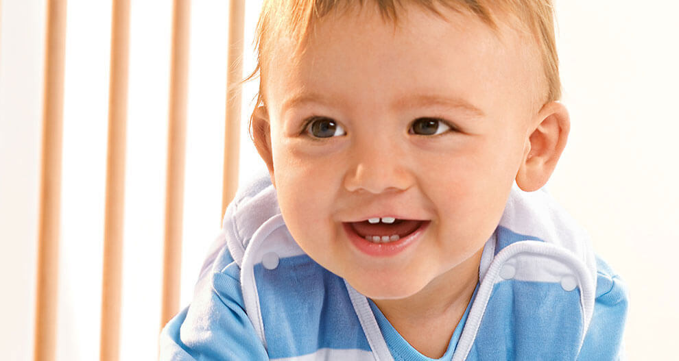 A toddler in a blue and white striped shirt is smiling and looking to the side.