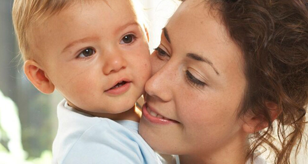 A woman lovingly embraces a baby.