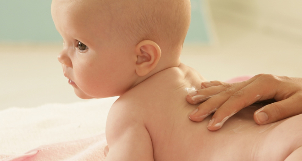 Baby receiving a lotion application.