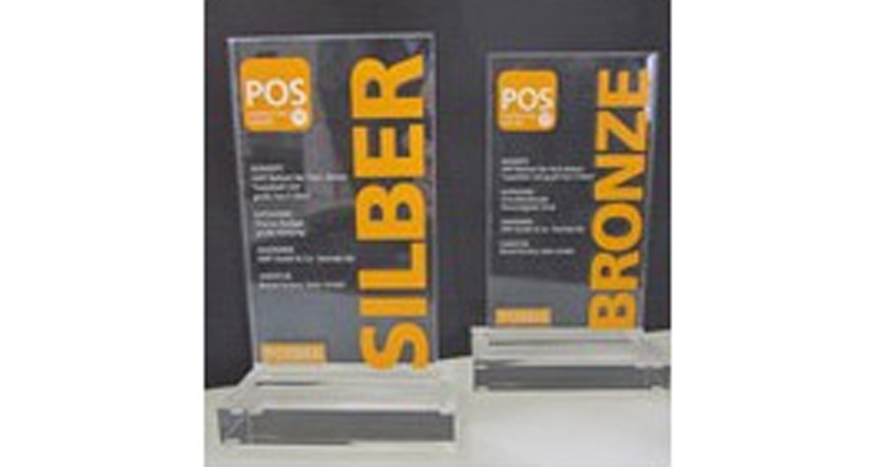 Two vertical, transparent award plaques stand side by side, each with the word "POS" at the top, followed by the words "SILBER" and "BRONZE" respectively, indicating different categories or levels of achievement in a competition or event.